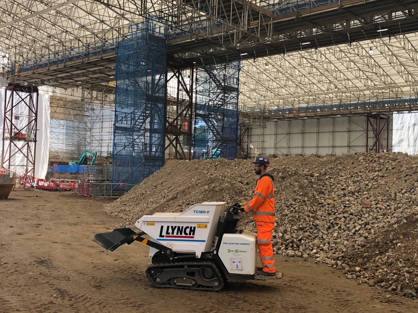 A picture of a worker on an electric one tonne wheelbarrow with front loading capacity