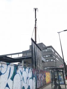 A picture of a demolition curtain next to a pubic footpath and bus stop