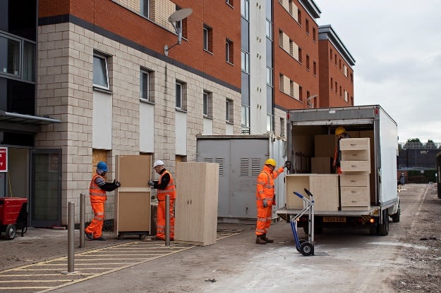 Picture of three workers in PPE delivering bedroom furniture for homeless shelters 