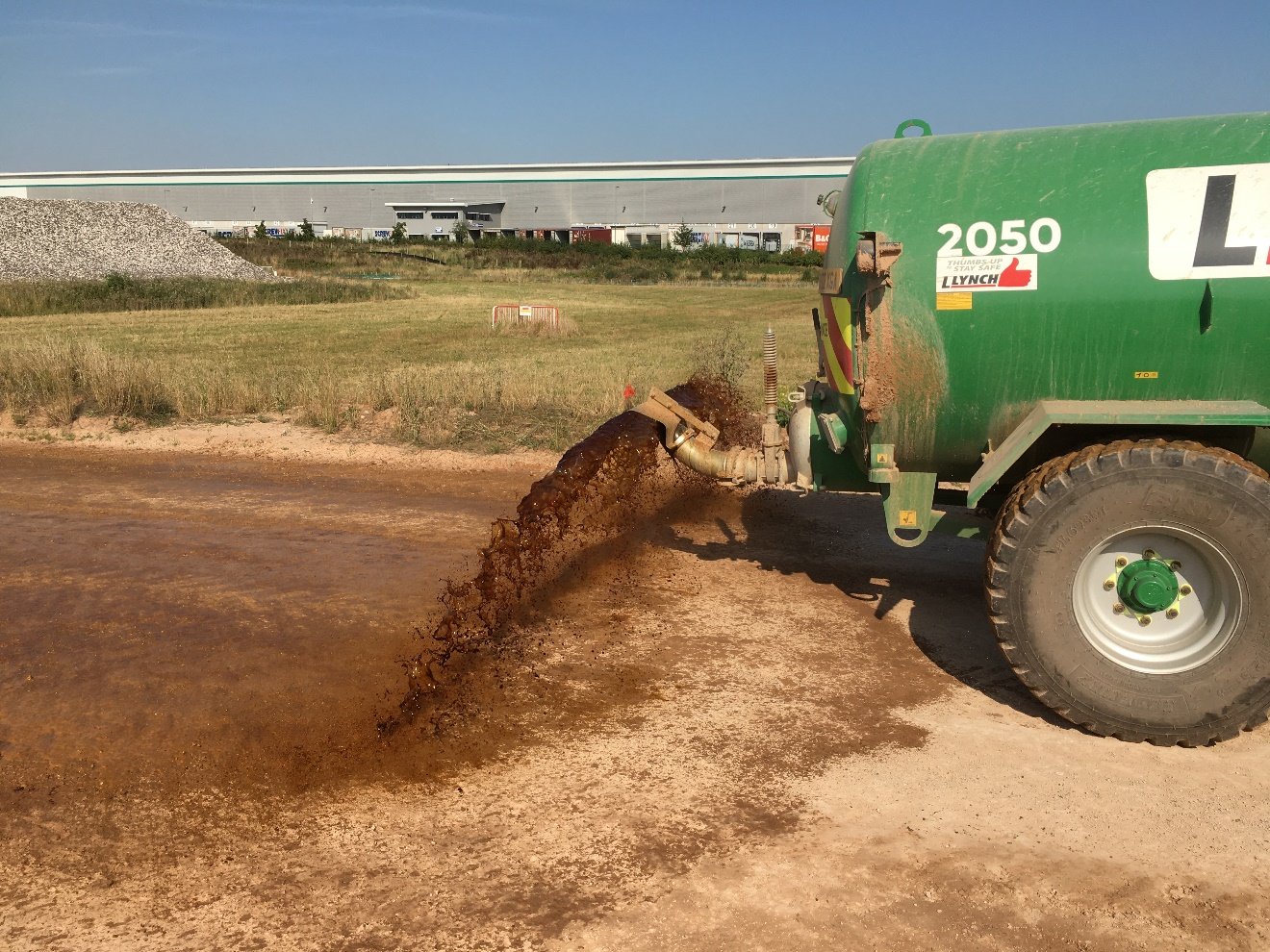 A green truck pouring additive application 

