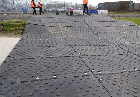 A group of workers laying trackway on top of grass 
