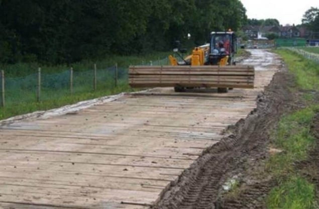 Worker in a truck laying bog mats.